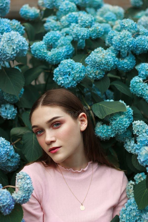 Close up portrait of the beautiful young brunette girl with bright makeup wearing pink t-shirt standing among blue stock photo Close up portrait of the beautiful young brunette girl with bright makeup wearing pink t-shirt standing among blue stock photo