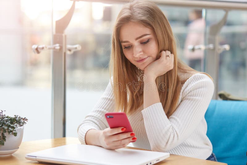 Close up portrait of charming female using mobile phone during break between lectures in coffee shop, young student holding her royalty free stock photography Close up portrait of charming female using mobile phone during break between lectures in coffee shop, young student holding her royalty free stock photography