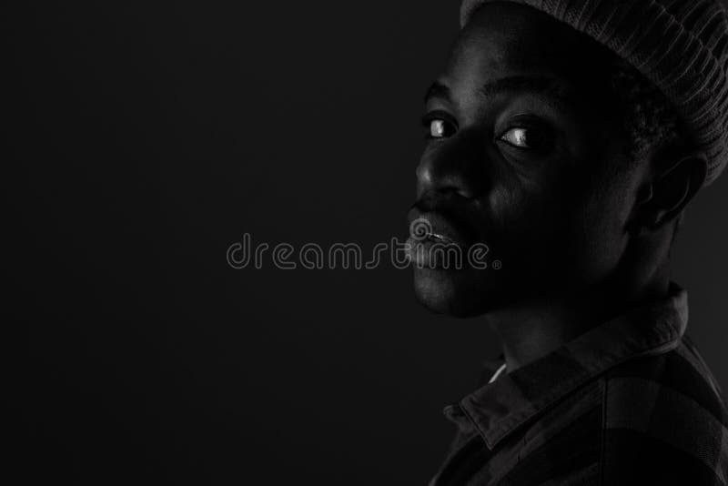 Close-up portrait of a charming handsome black guy with closed eyes in black and white light.