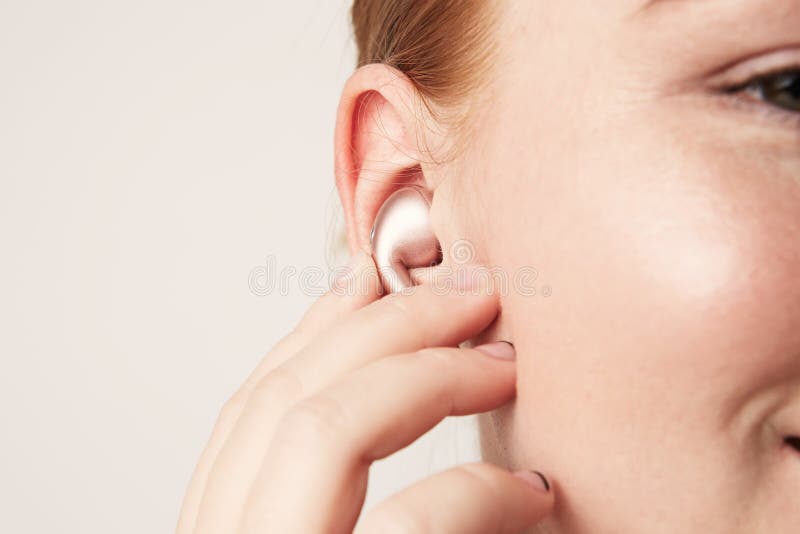 Close-up portrait of charming redhead caucasian woman with happy smile listening music with wireless earphone in ear. stock photography Close-up portrait of charming redhead caucasian woman with happy smile listening music with wireless earphone in ear. stock photography