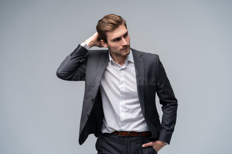 Close up portrait of a handsome young businessman dressed in suit isolated over gray background, looking away. stock photo Close up portrait of a handsome young businessman dressed in suit isolated over gray background, looking away. stock photo
