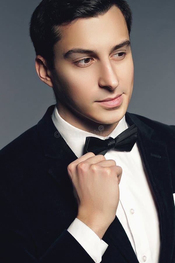 Close-up portrait of handsome young man in suit and bow tie on w