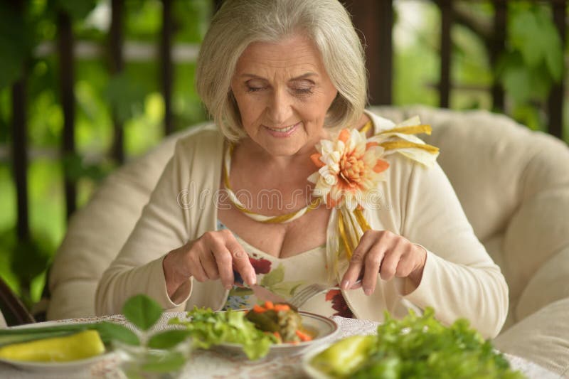 Portrait of happy senior woman eating delicious salad