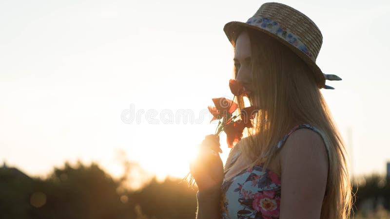 Close up portrait of lovely young romantic woman with poppy flower in hand posing on field background. Wearing straw hat. Sunlight background stock images Close up portrait of lovely young romantic woman with poppy flower in hand posing on field background. Wearing straw hat. Sunlight background stock images