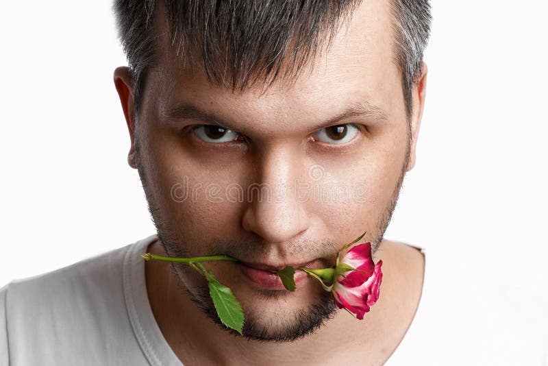 Close-up portrait of a man`s face with a rose in his mouth on a white background. Close-up