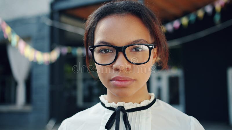 Close-up portrait of pretty African American girl with serious face outdoors