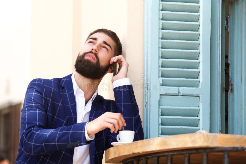 Close up serious businessman sitting at cafe with coffee talking on cellphone