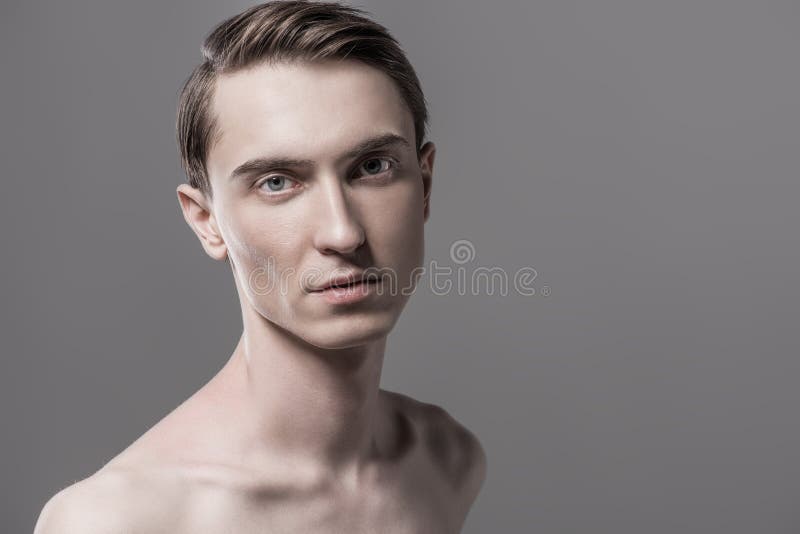 Shirtless slender man. Close-up portrait of a shirtless young man. Gray background. Men`s beauty and health