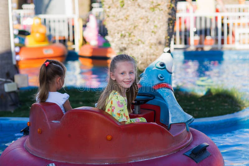 Close-up portrait of a smiling girl near the carousel at the fair. Happy child having fun in the amusement park. happy childhood