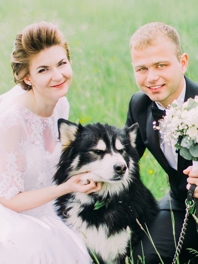 The Close Up Portrait Of The Smiling Newlyweds Petting The Dog In The