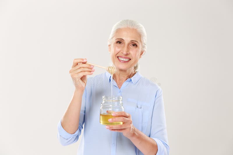 Close-up portrait of smiling old woman, holding honey jar with s royalty free stock images Close-up portrait of smiling old woman, holding honey jar with s royalty free stock images