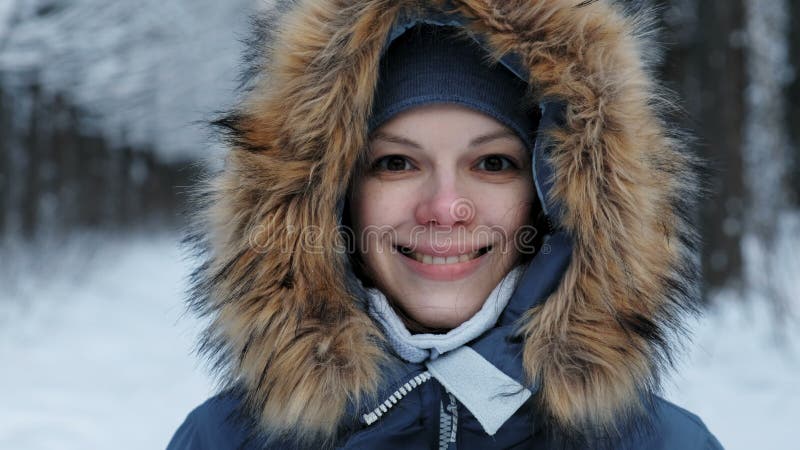 Close-up portrait of a smiling woman in a hoodie with fur on the street.