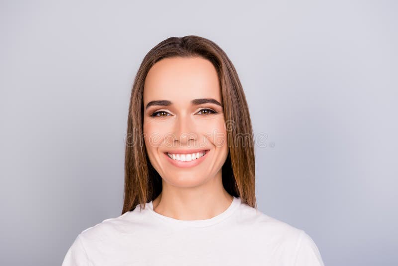 Portretul de succes al tinerei femei cu părul brun antreprenor în tricoul alb cu părul alb, așezat pe gri pur deschis royalty free stock image