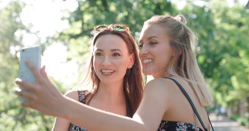 Two beautiful teenage girls using phone in a city park. Two beautiful teenage girls using phone in a city park.