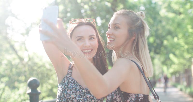 Two beautiful teenage girls using phone in a city park. Two beautiful teenage girls using phone in a city park.