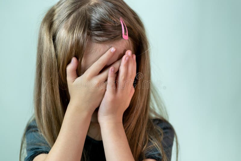 Close-up portrait of unhappy little girl with long hair covering her face with hands crying stock photography Close-up portrait of unhappy little girl with long hair covering her face with hands crying stock photography