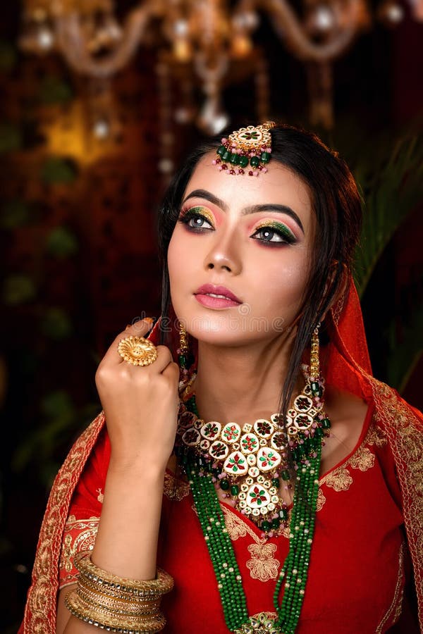 Close up portrait of very beautiful young Indian bride in luxurious bridal costume with makeup and heavy jewellery in studio