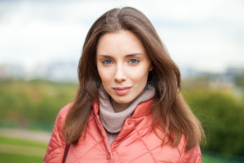 Close Up Portrait Of A Young Beautiful Brunette Girl In Coral Coat 