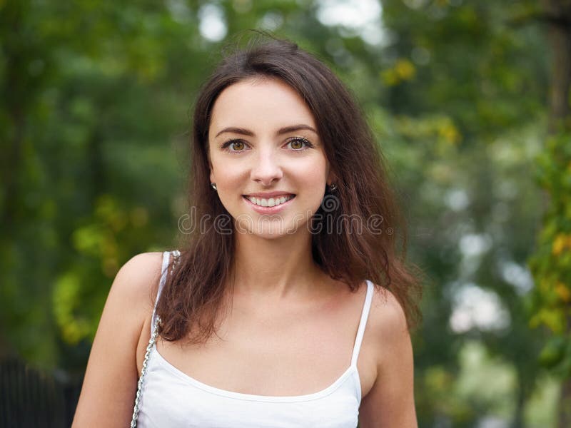 Close up portrait of young beautiful brunette woman with adorable smile enjoying sunlight in city park stock photography Close up portrait of young beautiful brunette woman with adorable smile enjoying sunlight in city park stock photography