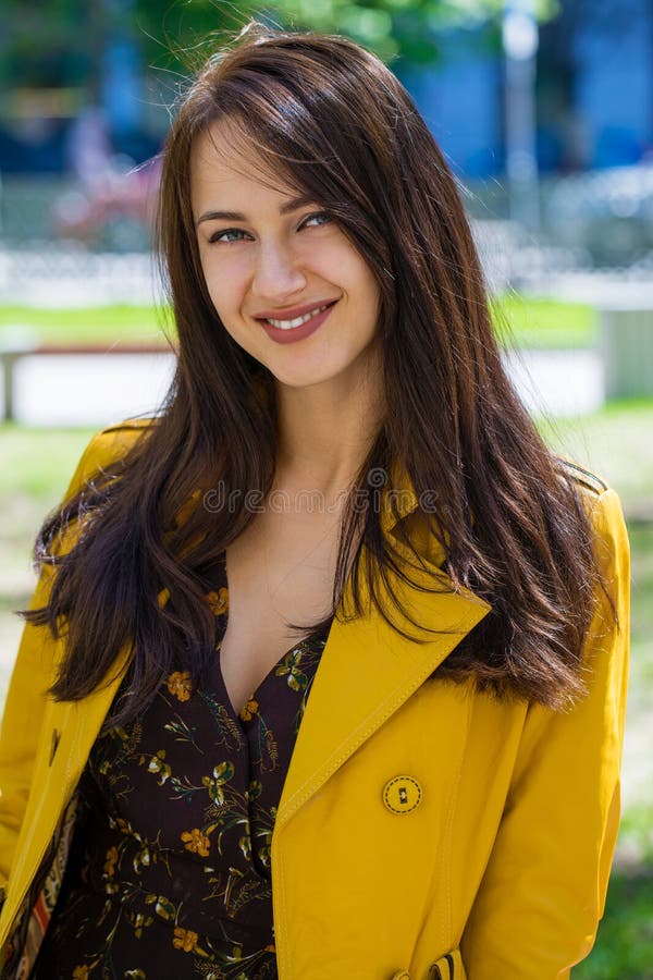 Portrait of young beautiful brunette in yellow jacket. Happy, clothes.