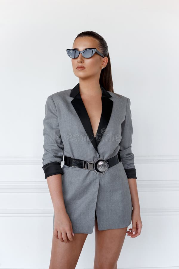 Close up portrait of a young confident girl in grey jacket with sunglasses, looking at the side, over white background