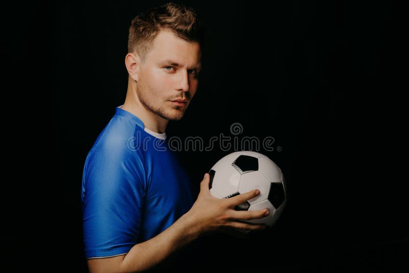 Close-up portrait of young handsome football player soccer posing on dark background. stock photos Close-up portrait of young handsome football player soccer posing on dark background. stock photos