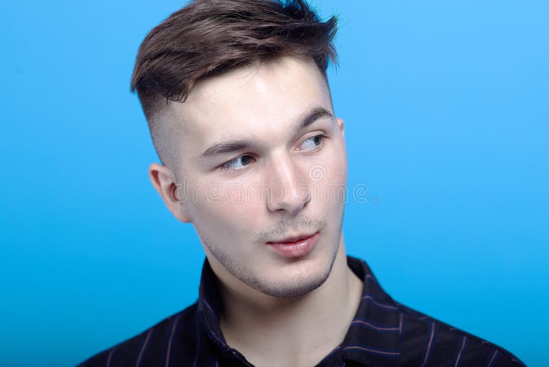 Close up portrait of young handsome man with astonished grimace on blue background. Fashion hairstyle, strong emotions, expressiv royalty free stock image Close up portrait of young handsome man with astonished grimace on blue background. Fashion hairstyle, strong emotions, expressiv royalty free stock image