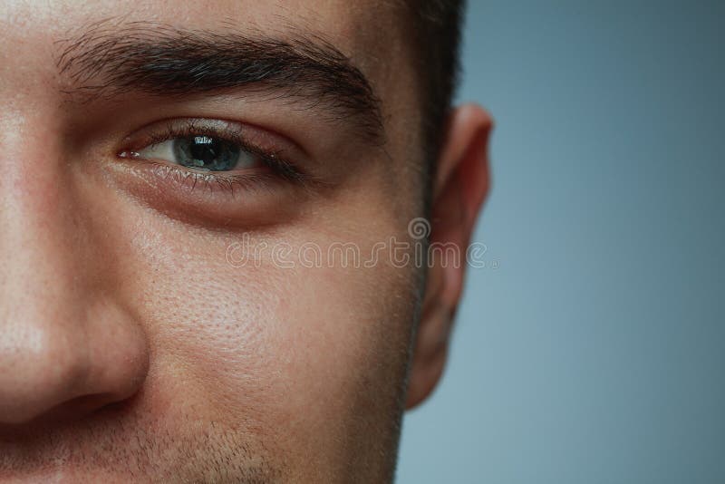 Close-up portrait of young man isolated on grey studio background