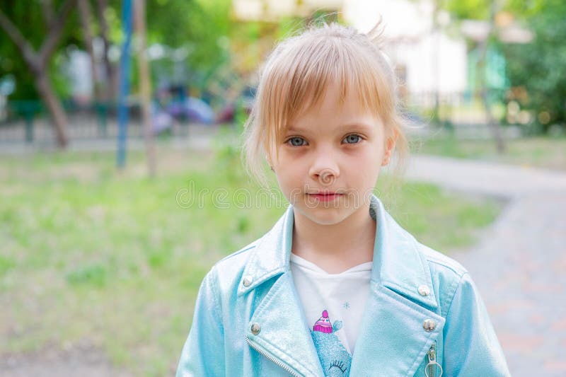 Close up portrait of young 6-7 year old girl. Girl 7 years old outdoors portrait in a blue jacket