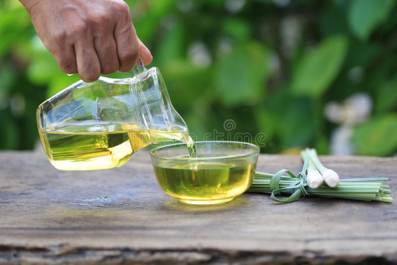 Close up of Pouring lemongrass essential oil to glass bottles on natural green background