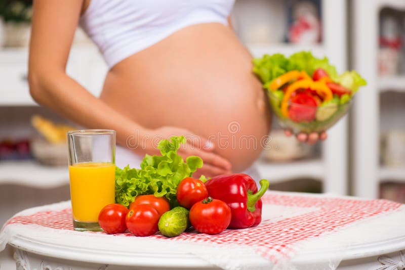 Close-up of a pregnant belly. Women's Health, fortified food. Fresh vegetables, diet and figure