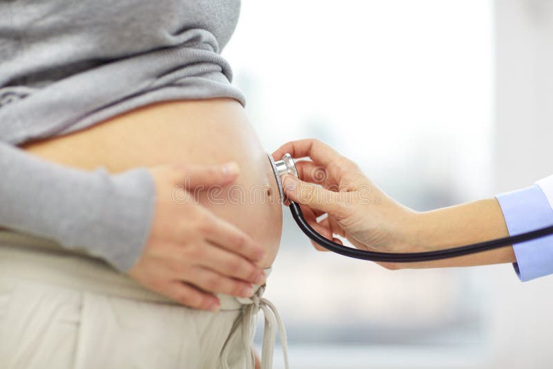 Close up of pregnant woman belly and doctor hand stock photo Close up of pregnant woman belly and doctor hand stock photo
