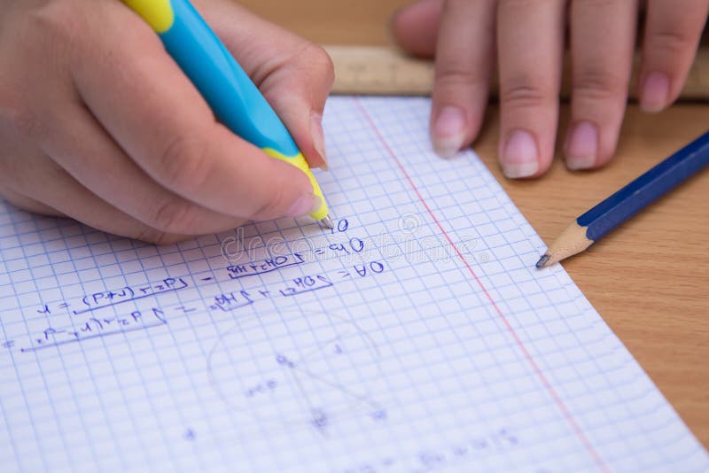 Close-up pupil& x27;s hand solves a geometric problem in a notebook. stock photos