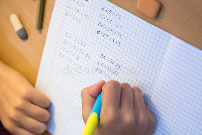 Close-up pupil& x27;s hand solves math examples in a notebook. royalty free stock image