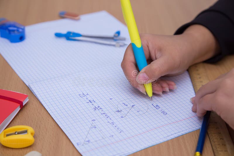 Close-up pupil& x27;s hand writes a geometric formula in a notebook. royalty free stock image