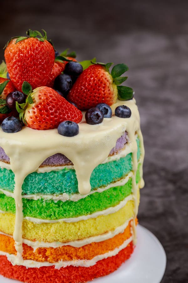 Close up of rainbow sponge cake decorated with fresh berries stock photos