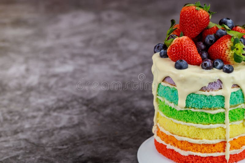 Close up of rainbow sponge cake decorated with fresh berries stock photography
