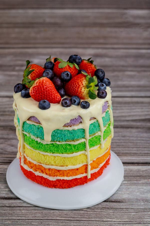 Close up of rainbow sponge cake decorated with fresh berries stock photos