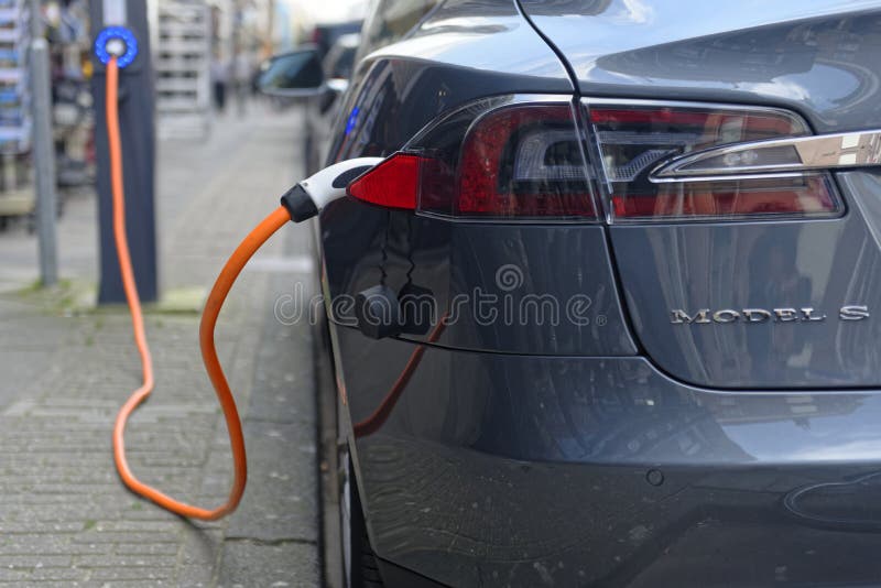 A close up of the rear of a Tesla Model S charging on a street.