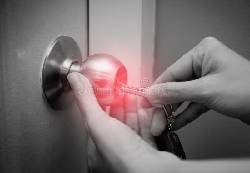 Close up of red spot of woman`s hand using key for unlocking or locking the white door royalty free stock images
