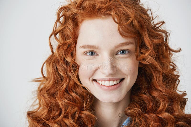 Close Up Of Redhead Beautiful Girl With Freckles Smiling Looking At Camera Over White Background