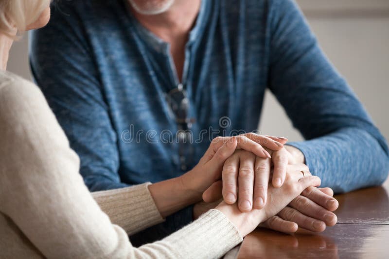 Close up of romantic aged couple holding hands caressing