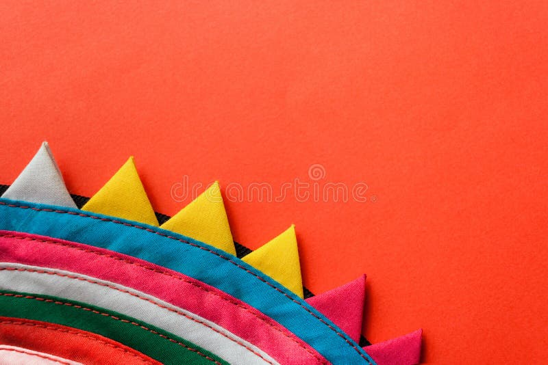 Close-up round colorful handmade striped stitched fabric with triangular edge on red background. royalty free stock photos Close-up round colorful handmade striped stitched fabric with triangular edge on red background. royalty free stock photos