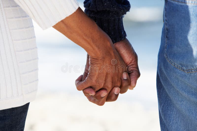 Close Up Of Senior Couple Holding Hands On Beach