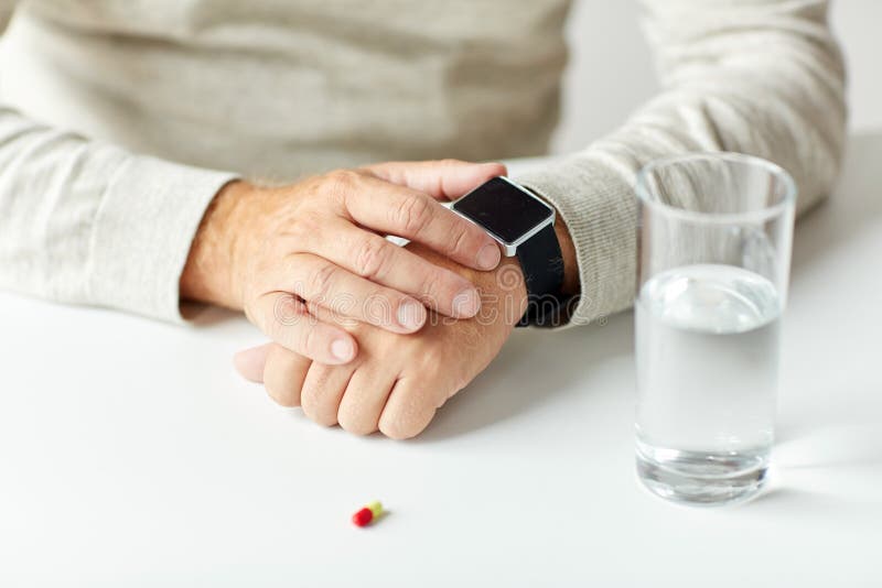 Close up of senior man with water, pill and watch