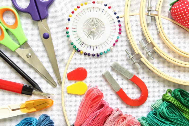 Close-up sewing and embroidery kit with threads and needle, button, scissors and fabrics on frame royalty free stock image Close-up sewing and embroidery kit with threads and needle, button, scissors and fabrics on frame royalty free stock image