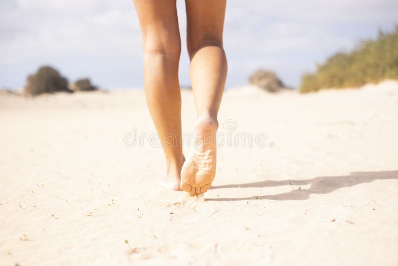 Close up of sexy nude young beautiful woman legs walking on the soft sand at the beach in summer holiday free vacation - concept