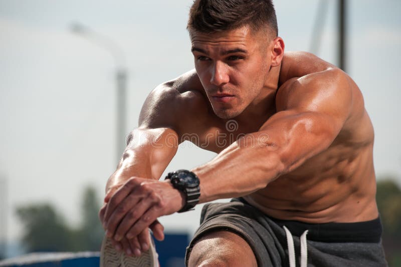 Close-up shirtless young male jogger warmimg up