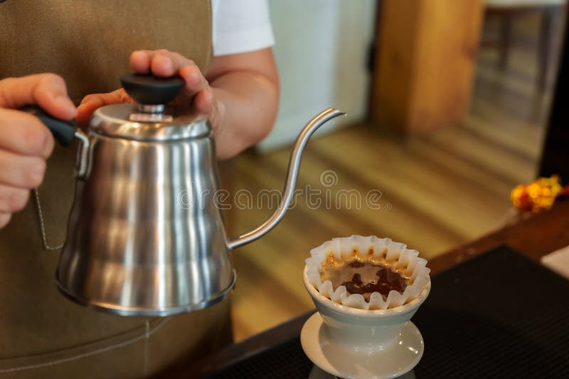 O lovitură de închidere a femeii asiatice barmane care ridică ceainicul turnând apă peste cafea. pentru a face cafea picurată pent stock images