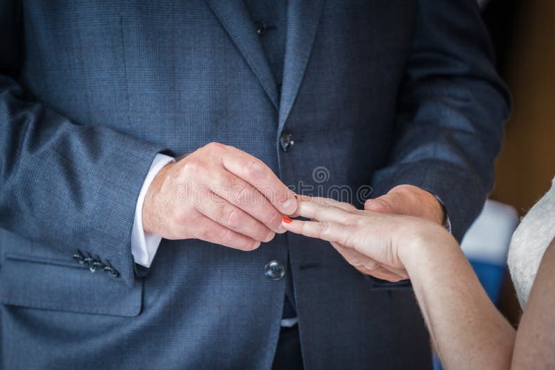 Close up shot of bride holding out hand as groom at wedding ceremony placing ring on finger whilst saying vows and I do to seal th